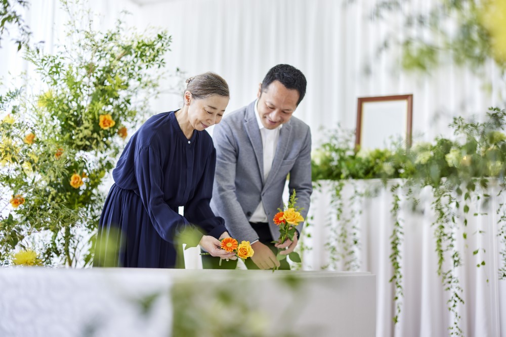 女性と男性が棺の中に花を入れている